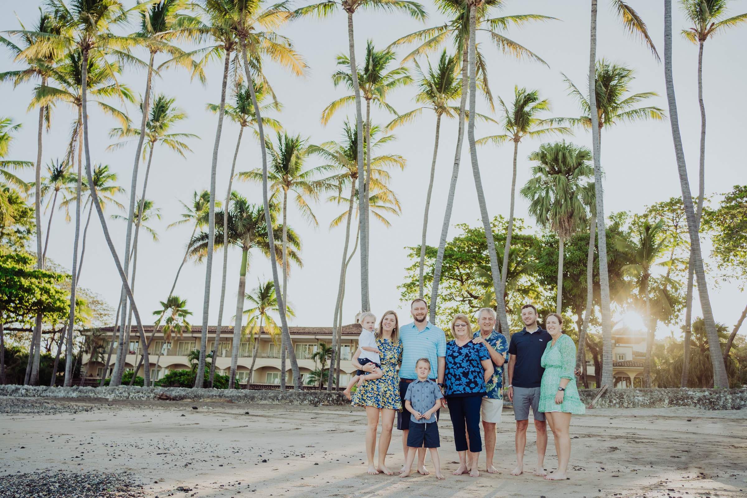 Three generations of one family on the beach at Tamarindo, Costa Rica, palms behind them in the late afternoon light